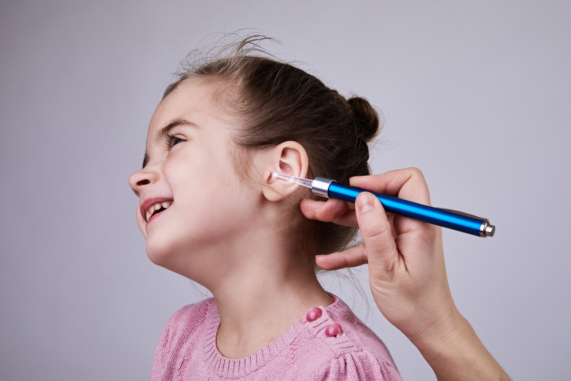 Docteur examinant l’oreille de la fille avec le stylo médical de lampe de poche.